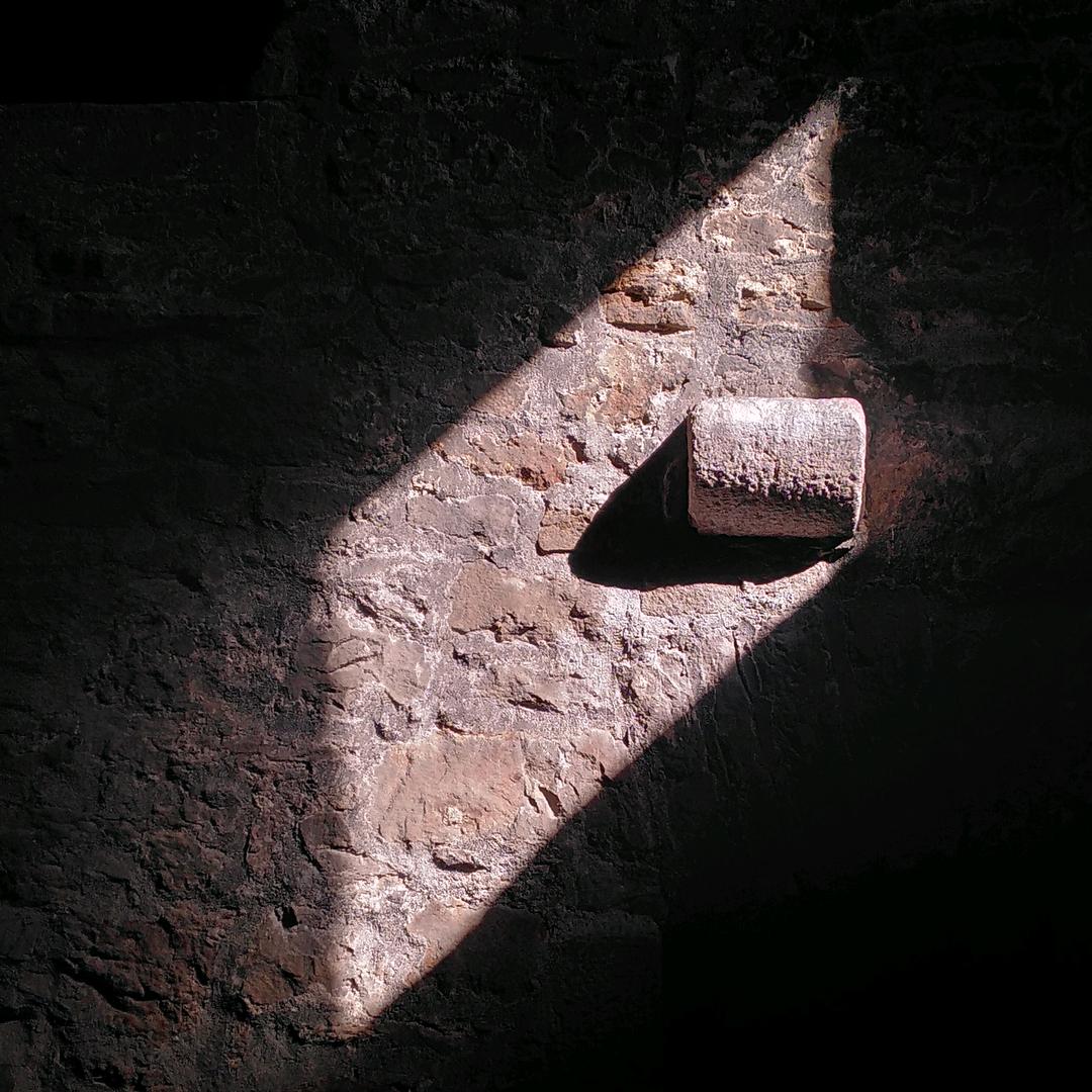 Shadow cast by a stone on a stone wall.